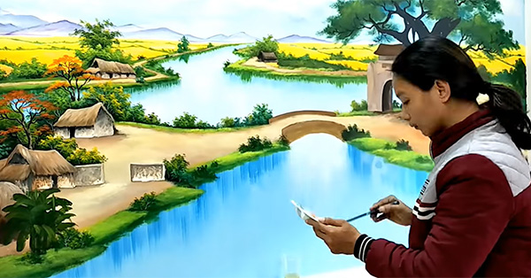 Họa sĩ đang vẽ tranh tường đồng quê hình ảnh cây đa, đình làng cho khách hàng tại Hưng Yên
